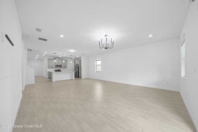 unfurnished living room with light hardwood / wood-style floors and a chandelier