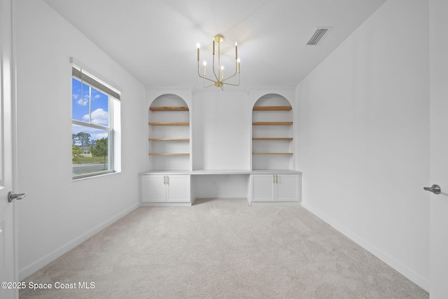 interior space featuring light carpet, a chandelier, and built in desk