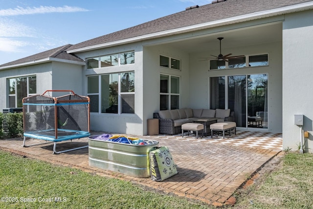 rear view of house featuring ceiling fan, a trampoline, a patio area, and an outdoor hangout area