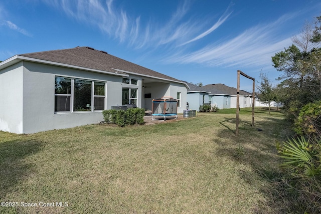 rear view of property with a yard and a trampoline