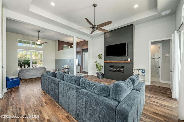 living room featuring a raised ceiling, ceiling fan, and dark hardwood / wood-style floors