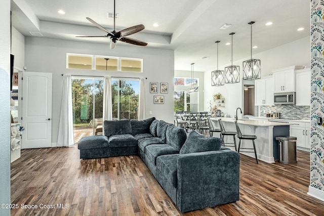 living room featuring ceiling fan, dark hardwood / wood-style flooring, and a high ceiling