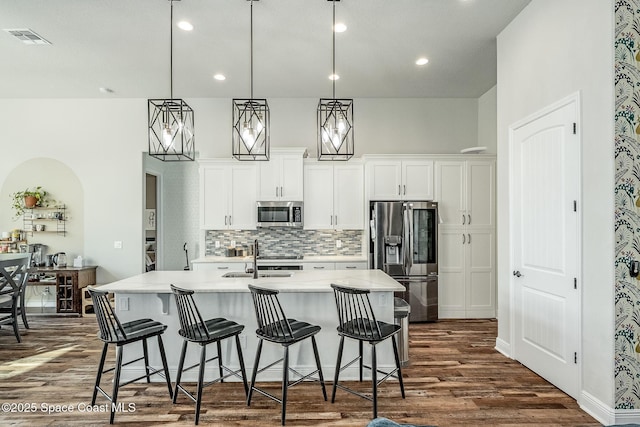 kitchen featuring hanging light fixtures, sink, an island with sink, appliances with stainless steel finishes, and white cabinetry