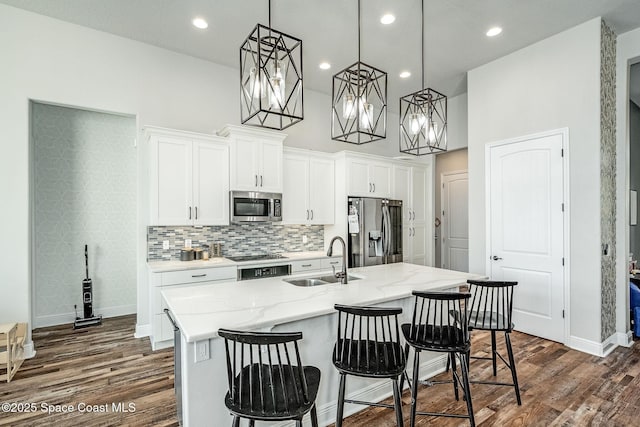 kitchen with pendant lighting, white cabinets, sink, an island with sink, and appliances with stainless steel finishes