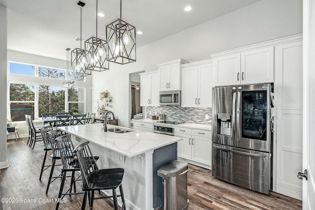 kitchen featuring white cabinetry, a center island with sink, hanging light fixtures, and appliances with stainless steel finishes