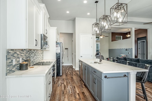 kitchen featuring pendant lighting, white cabinets, a spacious island, sink, and stainless steel appliances