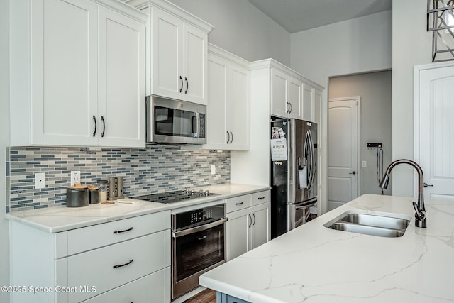 kitchen with light stone countertops, sink, decorative backsplash, white cabinets, and appliances with stainless steel finishes