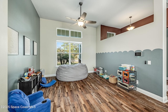 sitting room with dark hardwood / wood-style floors, ceiling fan, and a towering ceiling