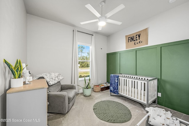 bedroom featuring ceiling fan, light colored carpet, and a nursery area