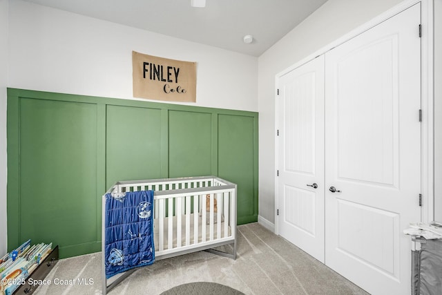 unfurnished bedroom with light carpet, a closet, and a nursery area