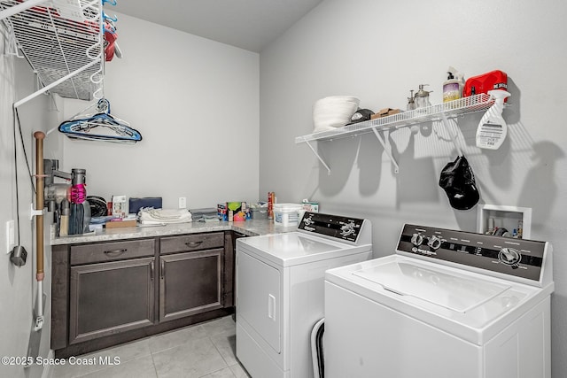 laundry room with cabinets, light tile patterned floors, and washer and dryer