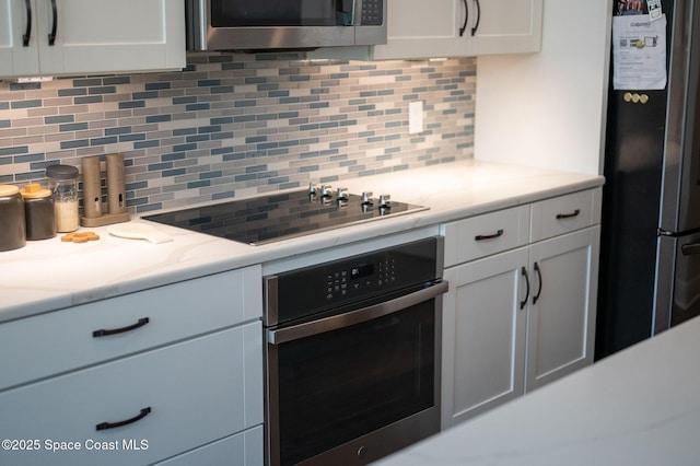 kitchen featuring white cabinets, appliances with stainless steel finishes, and backsplash