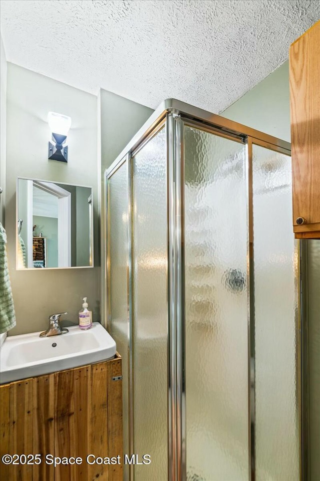 bathroom featuring a textured ceiling, vanity, and a shower with door