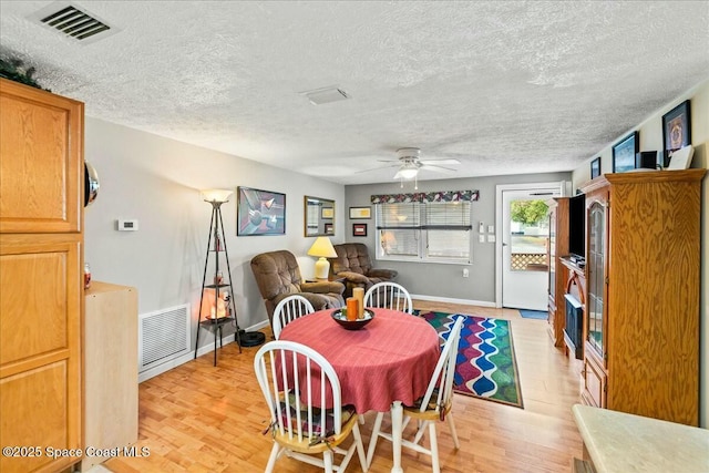 dining room with a textured ceiling, light hardwood / wood-style flooring, and ceiling fan