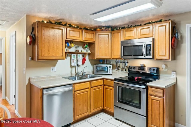 kitchen with sink, light tile patterned floors, a textured ceiling, and appliances with stainless steel finishes