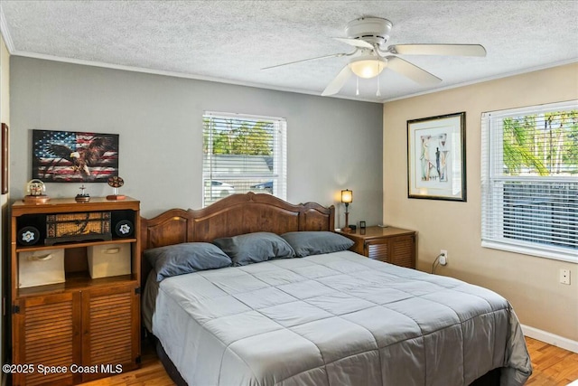 bedroom with ceiling fan, crown molding, wood-type flooring, and a textured ceiling