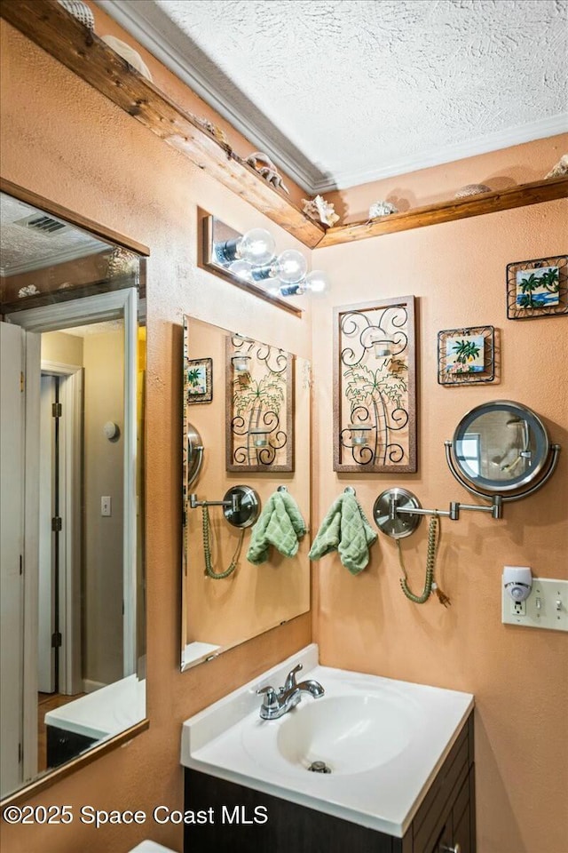 bathroom with vanity, a textured ceiling, and ornamental molding