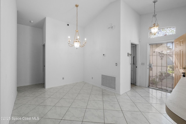 dining area featuring a towering ceiling, a healthy amount of sunlight, light tile patterned floors, and a notable chandelier