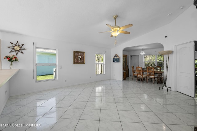 unfurnished living room with ceiling fan with notable chandelier, a healthy amount of sunlight, and lofted ceiling