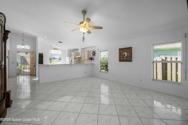 unfurnished living room featuring ceiling fan with notable chandelier and vaulted ceiling