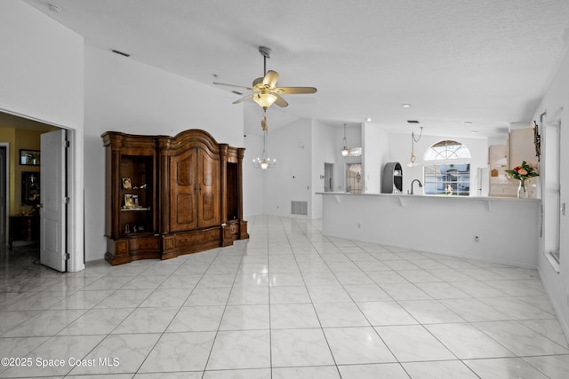 unfurnished living room featuring a textured ceiling, sink, high vaulted ceiling, and ceiling fan with notable chandelier