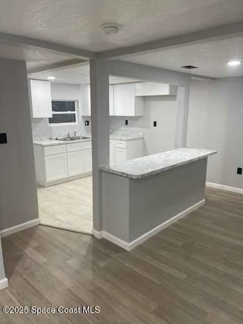 kitchen featuring white cabinets, sink, light stone countertops, a textured ceiling, and dark hardwood / wood-style flooring