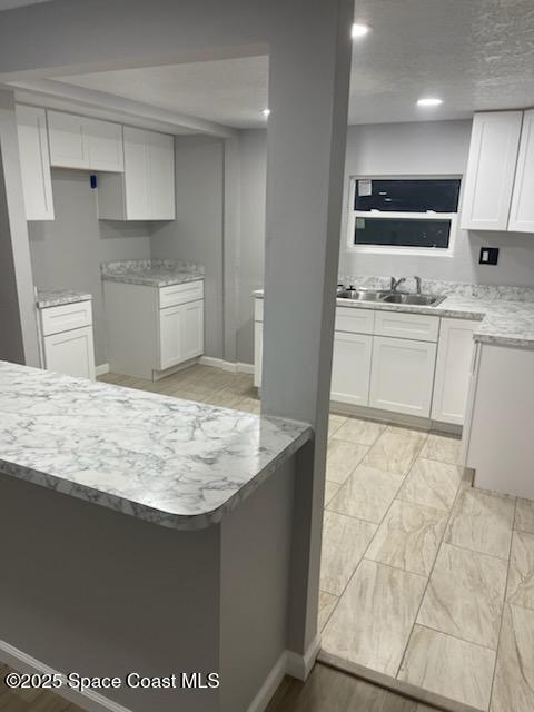 kitchen with white cabinets, kitchen peninsula, and sink