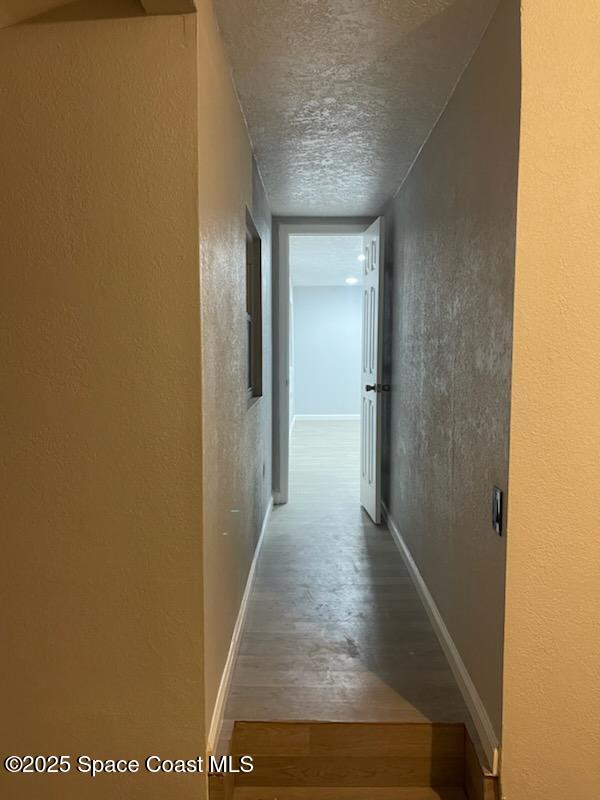 hallway featuring hardwood / wood-style floors and a textured ceiling