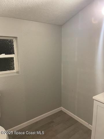 unfurnished room featuring dark hardwood / wood-style flooring and a textured ceiling