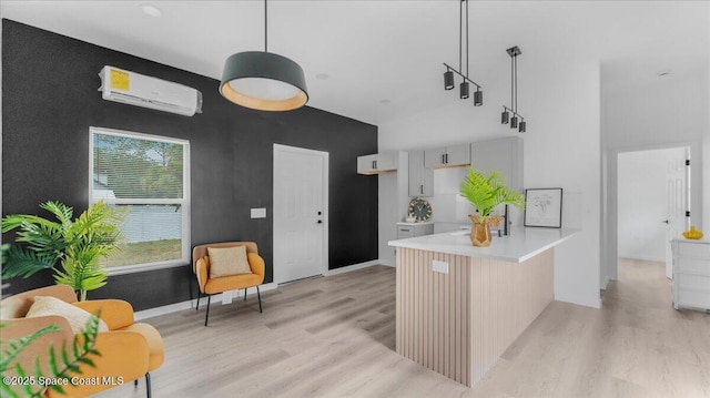 kitchen with hanging light fixtures, an AC wall unit, kitchen peninsula, light hardwood / wood-style floors, and gray cabinets