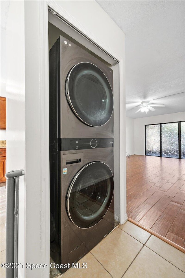 clothes washing area with tile patterned floors, ceiling fan, and stacked washer / dryer