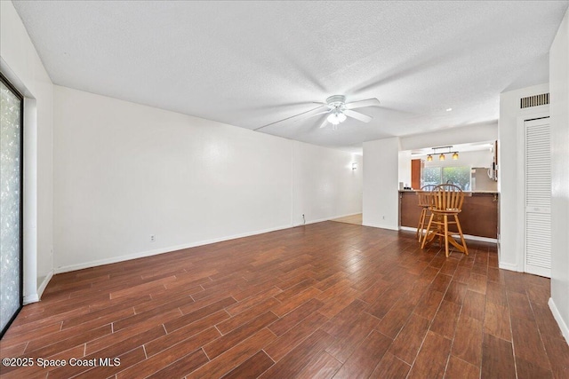 unfurnished living room with ceiling fan and a textured ceiling