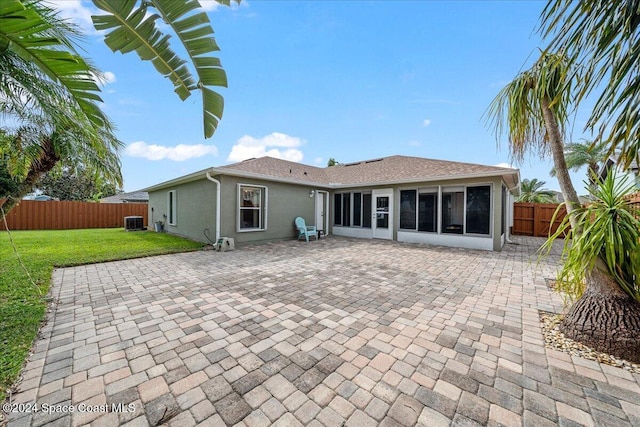 back of property with a sunroom, central AC unit, a patio area, and a yard