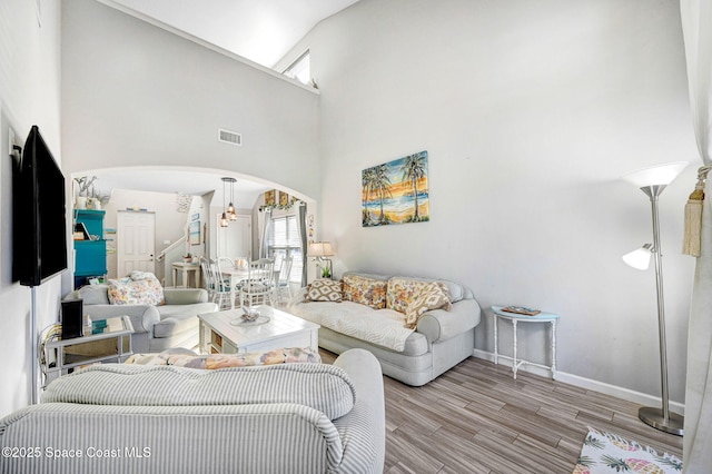 living room featuring an inviting chandelier, light hardwood / wood-style floors, and high vaulted ceiling