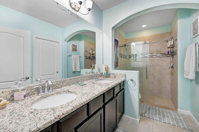 bathroom with a textured ceiling, tile patterned floors, a shower with door, vanity, and toilet