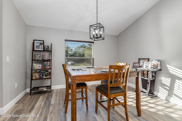 dining area with wood-type flooring and an inviting chandelier