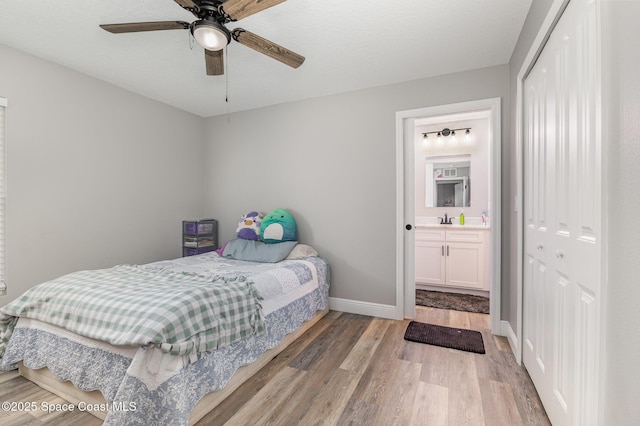 bedroom with ensuite bathroom, sink, ceiling fan, light wood-type flooring, and a closet