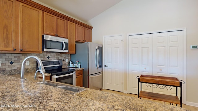 kitchen featuring lofted ceiling, sink, light wood-type flooring, tasteful backsplash, and stainless steel appliances