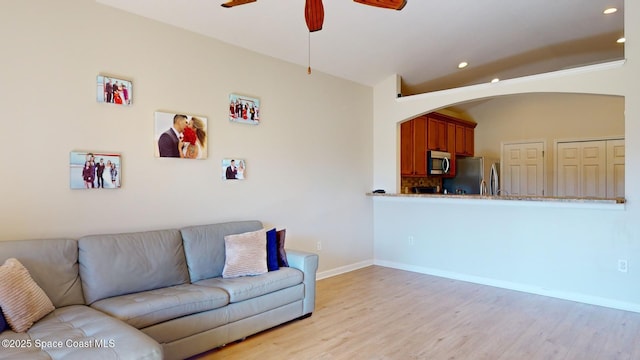 living room featuring light hardwood / wood-style flooring, ceiling fan, and lofted ceiling