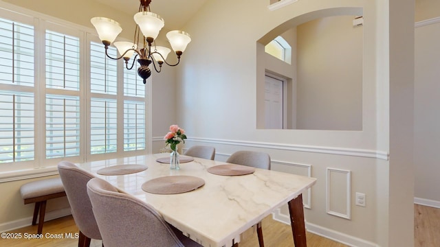 dining area with a healthy amount of sunlight, light hardwood / wood-style floors, and a notable chandelier