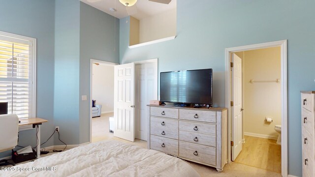 bedroom featuring multiple windows, ensuite bathroom, a towering ceiling, and ceiling fan