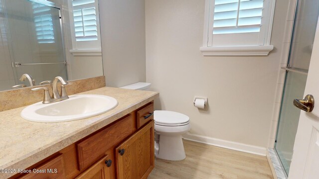 bathroom with hardwood / wood-style flooring, toilet, an enclosed shower, and a healthy amount of sunlight