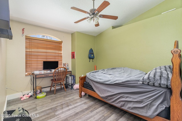 bedroom with a textured ceiling, light wood-type flooring, vaulted ceiling, and ceiling fan