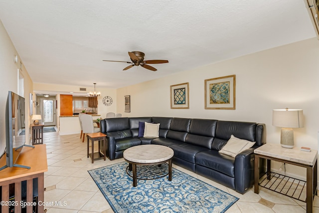 living room with ceiling fan with notable chandelier, light tile patterned floors, and a textured ceiling