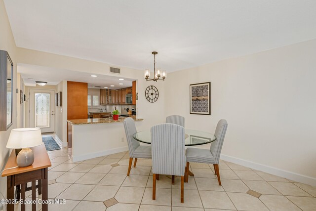 tiled dining room with an inviting chandelier