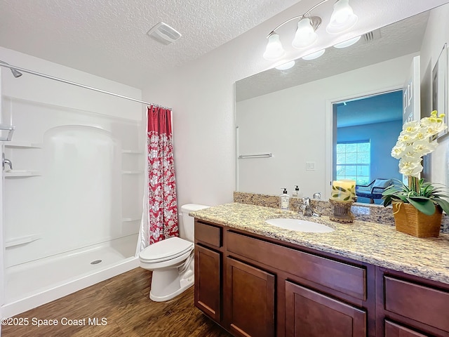 bathroom featuring hardwood / wood-style flooring, toilet, a textured ceiling, and walk in shower