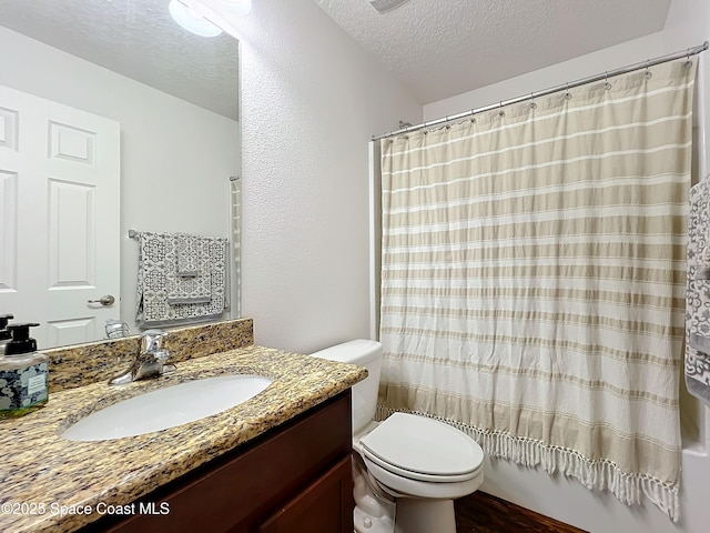 full bathroom featuring vanity, toilet, shower / bath combo with shower curtain, and a textured ceiling