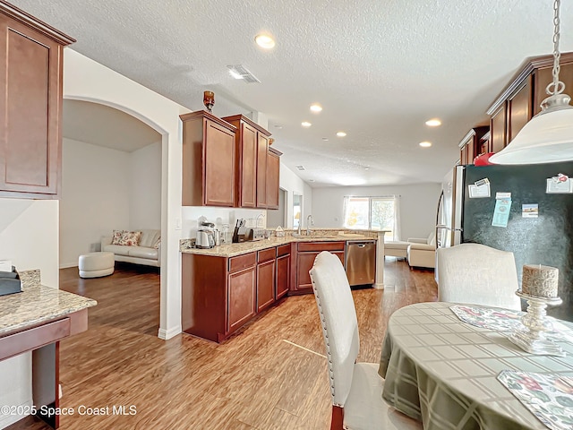 kitchen with hanging light fixtures, a textured ceiling, appliances with stainless steel finishes, light hardwood / wood-style floors, and kitchen peninsula