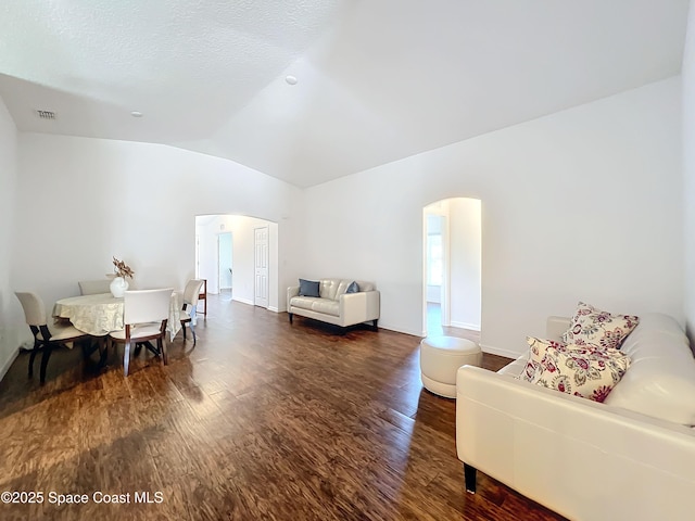 living room with a textured ceiling, dark hardwood / wood-style flooring, and vaulted ceiling