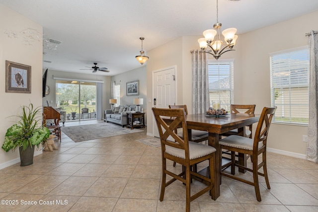 tiled dining room featuring ceiling fan with notable chandelier and a wealth of natural light